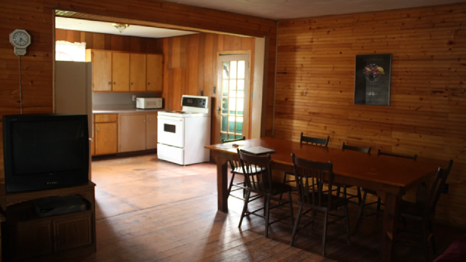 Pigeon Lake Resort Cottage Two.&nbsp; Open concept cottage interior with dining area, living room, and wood-paneled walls.